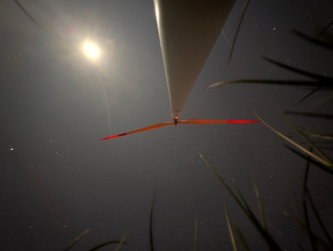 A quiet night scene with the lit windmill standing out against the star-filled sky.